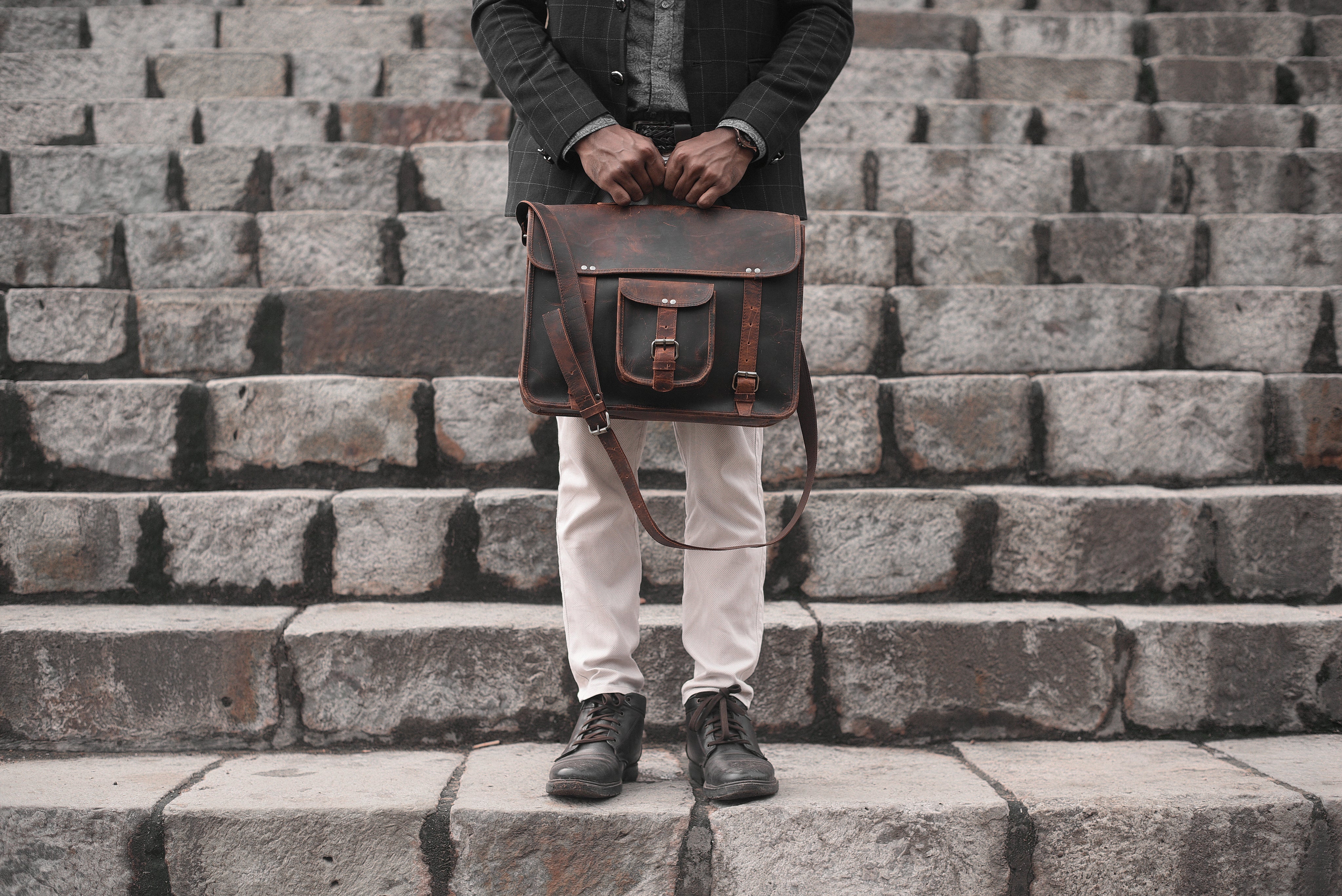 Man holding a leather bag on a set of stairs